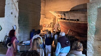 Grupo de personas en la la Cantera de Robadones con un barco antiguo en Menorca