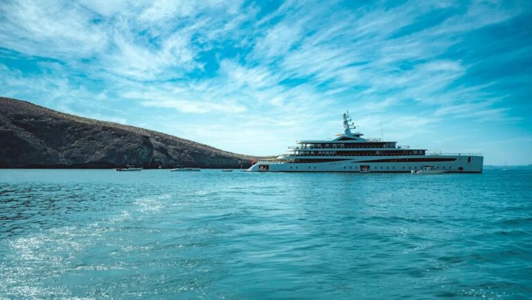 Yate de lujo navegando en aguas españolas con paisajes de fondo